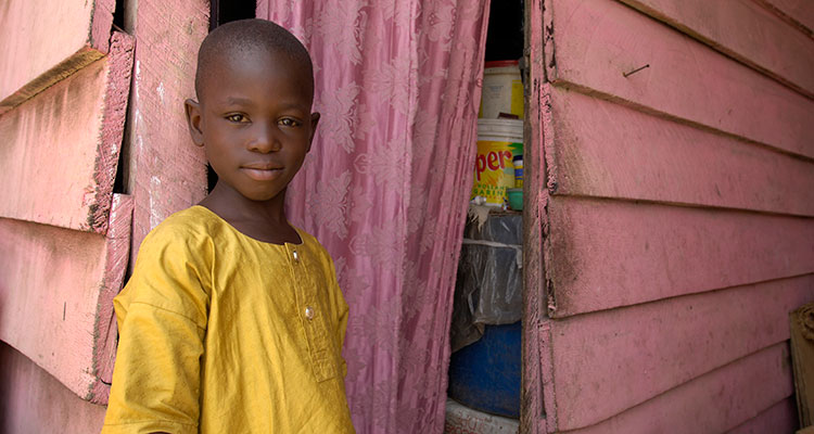 An African boy standing in the doorway of his home. The photography of Compassion International shows the dignity and hope living within the poor despite the oppression poverty inflicts upon them.